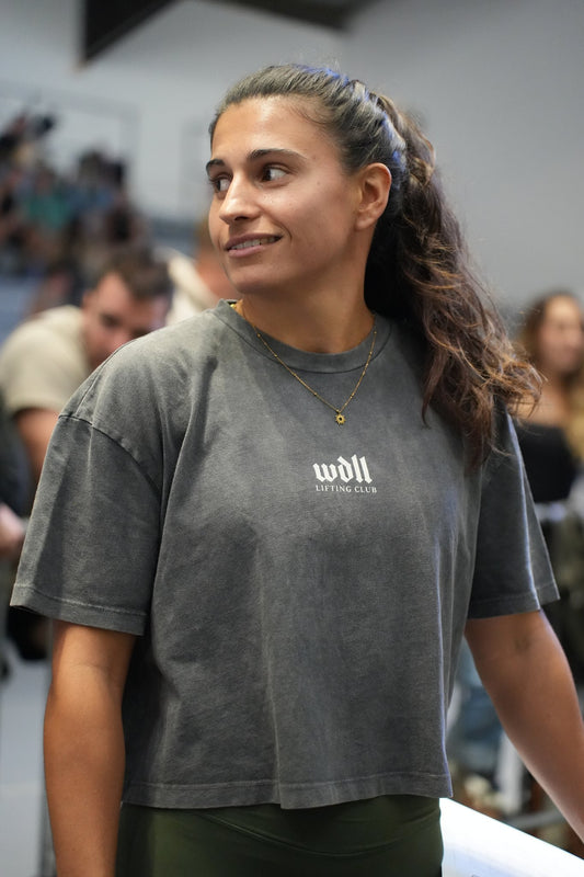 Crop top boxy WDLL Lifting Club International noir délavé porté de face, petit logo wdll poitrine – WOD.LOL