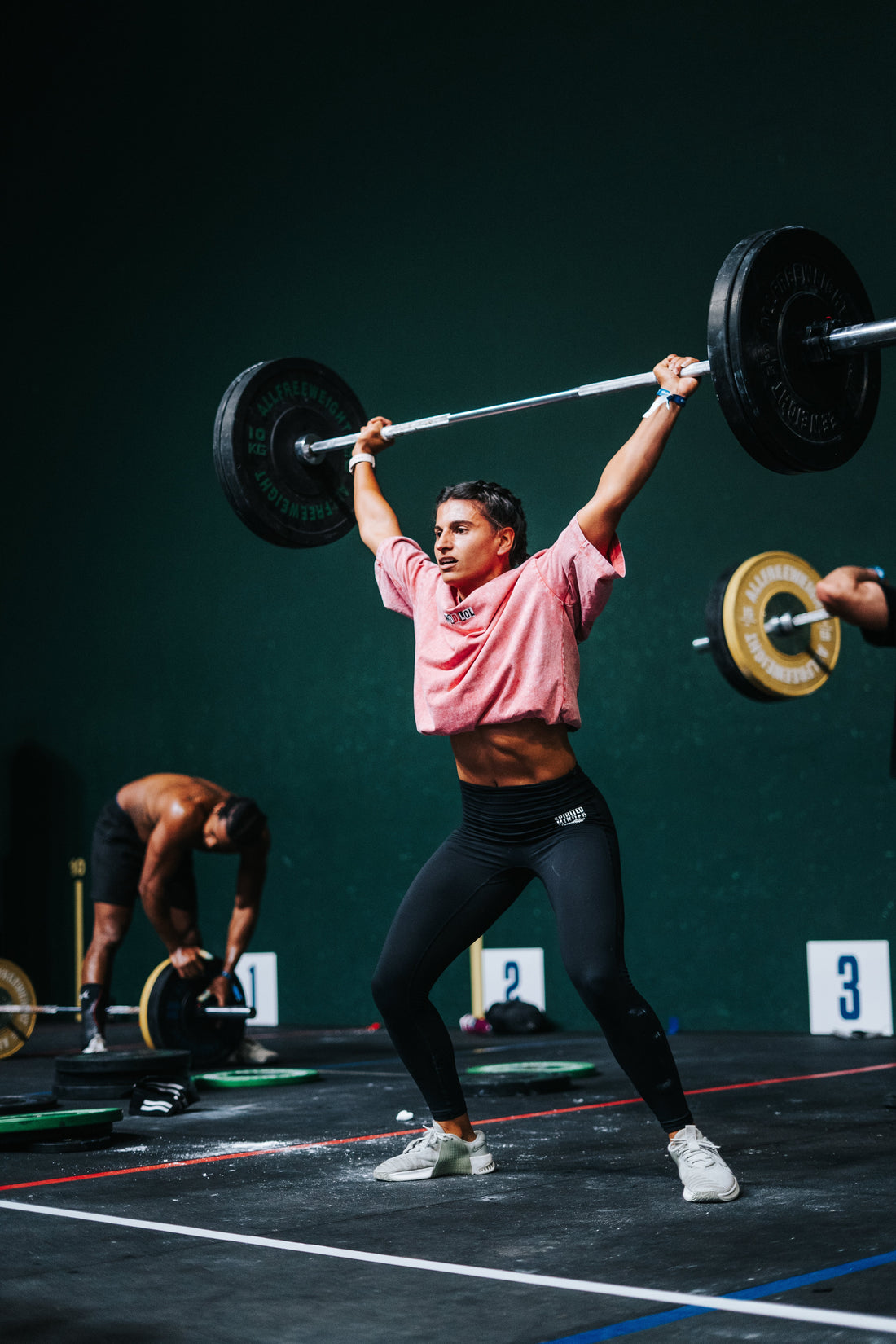 Athlète en squat overhead en compétition CrossFit, crop top WOD.LOL