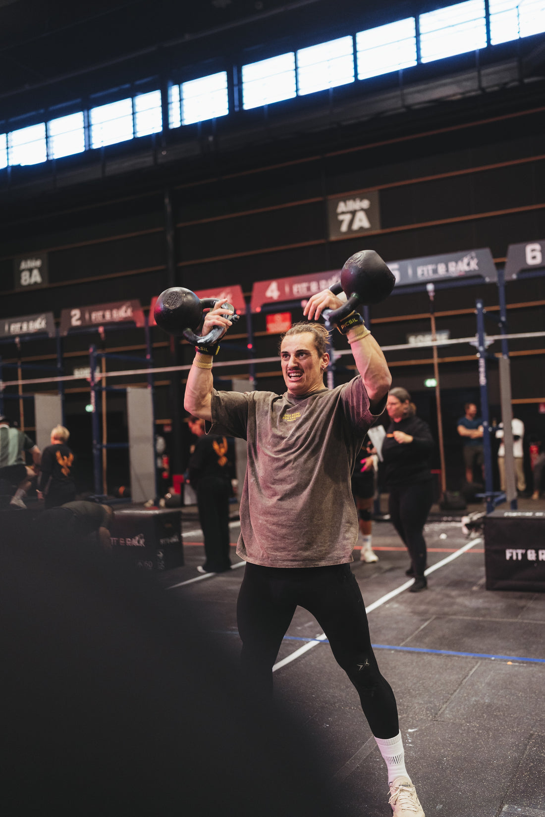 Athlète en plein swing kettlebell en compétition CrossFit