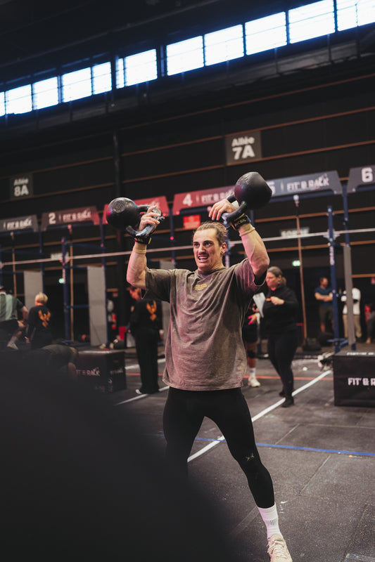 Athlète en plein swing kettlebell en compétition CrossFit