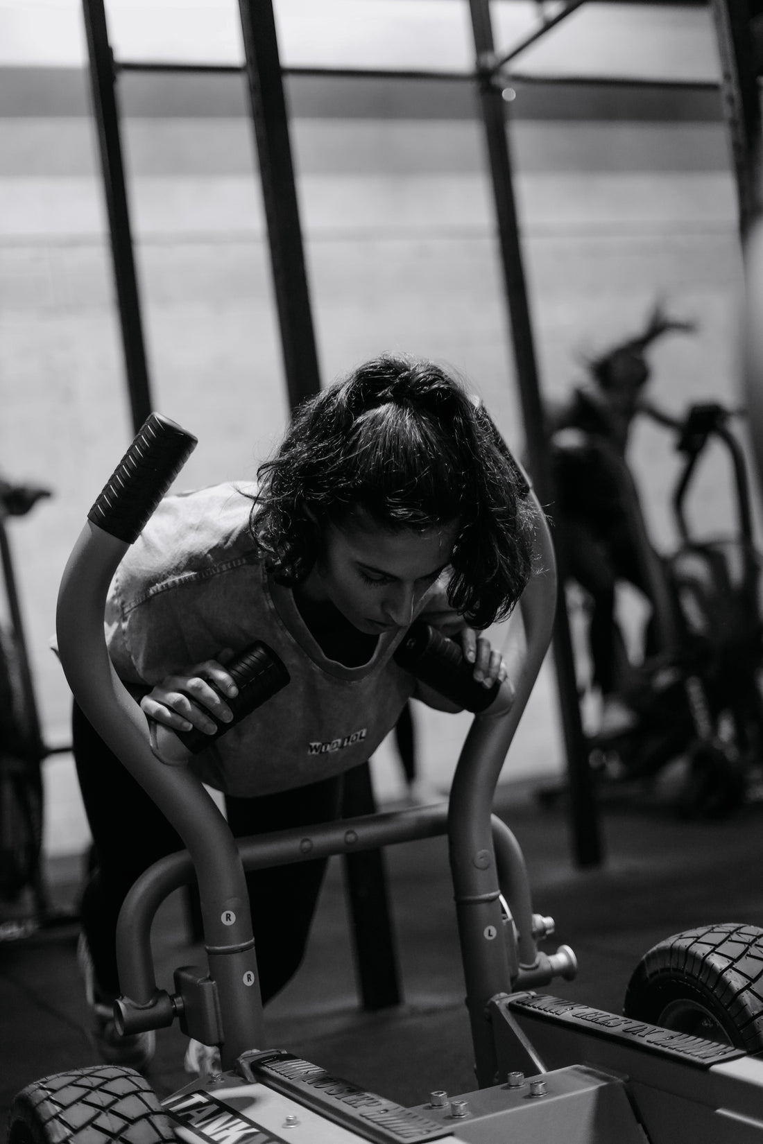 Athlète féminine sur un sled push, un des mouvements phares de Hyrox