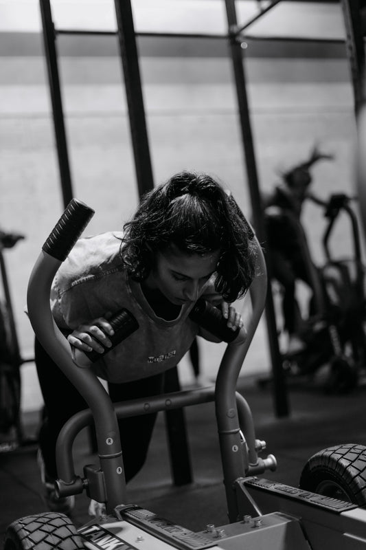 Athlète féminine sur un sled push, un des mouvements phares de Hyrox