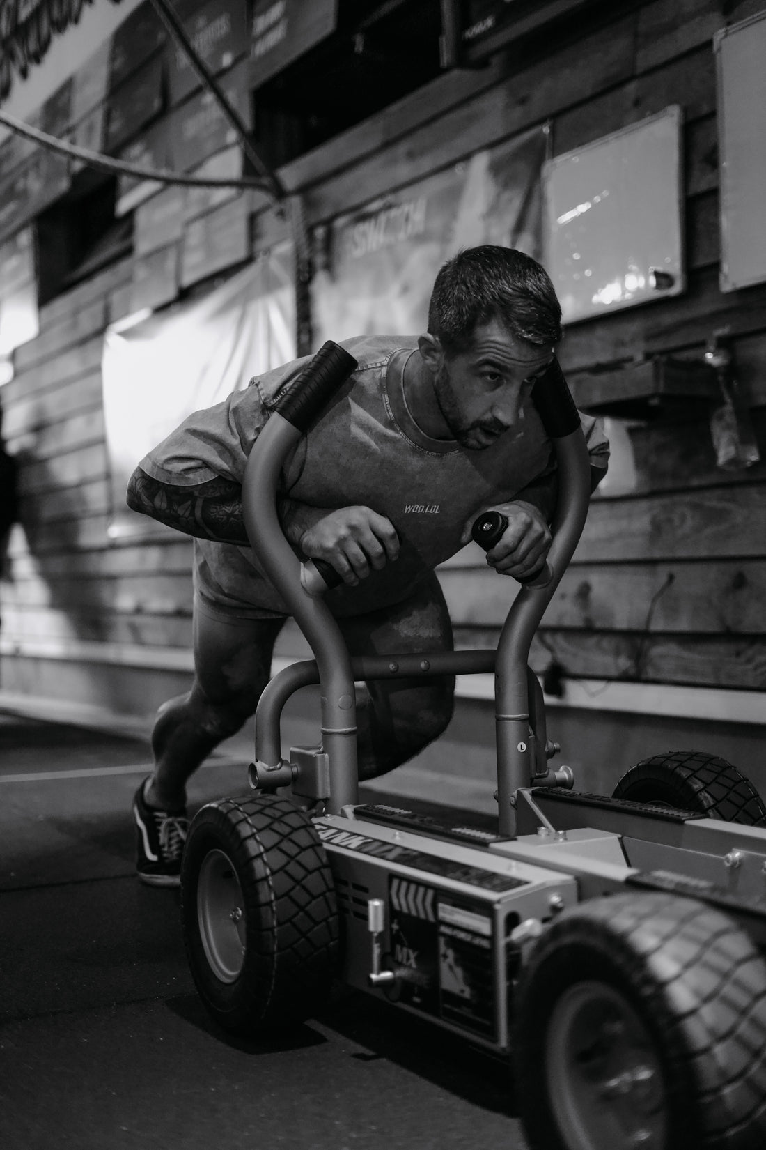 Athlète poussant un traîneau à l'effort en t-shirt WOD.LOL