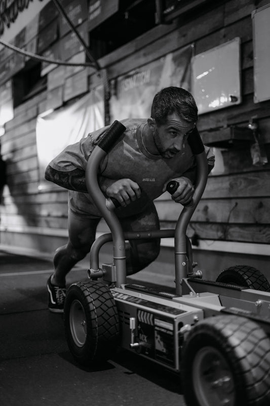 Athlète poussant un traîneau à l'effort en t-shirt WOD.LOL