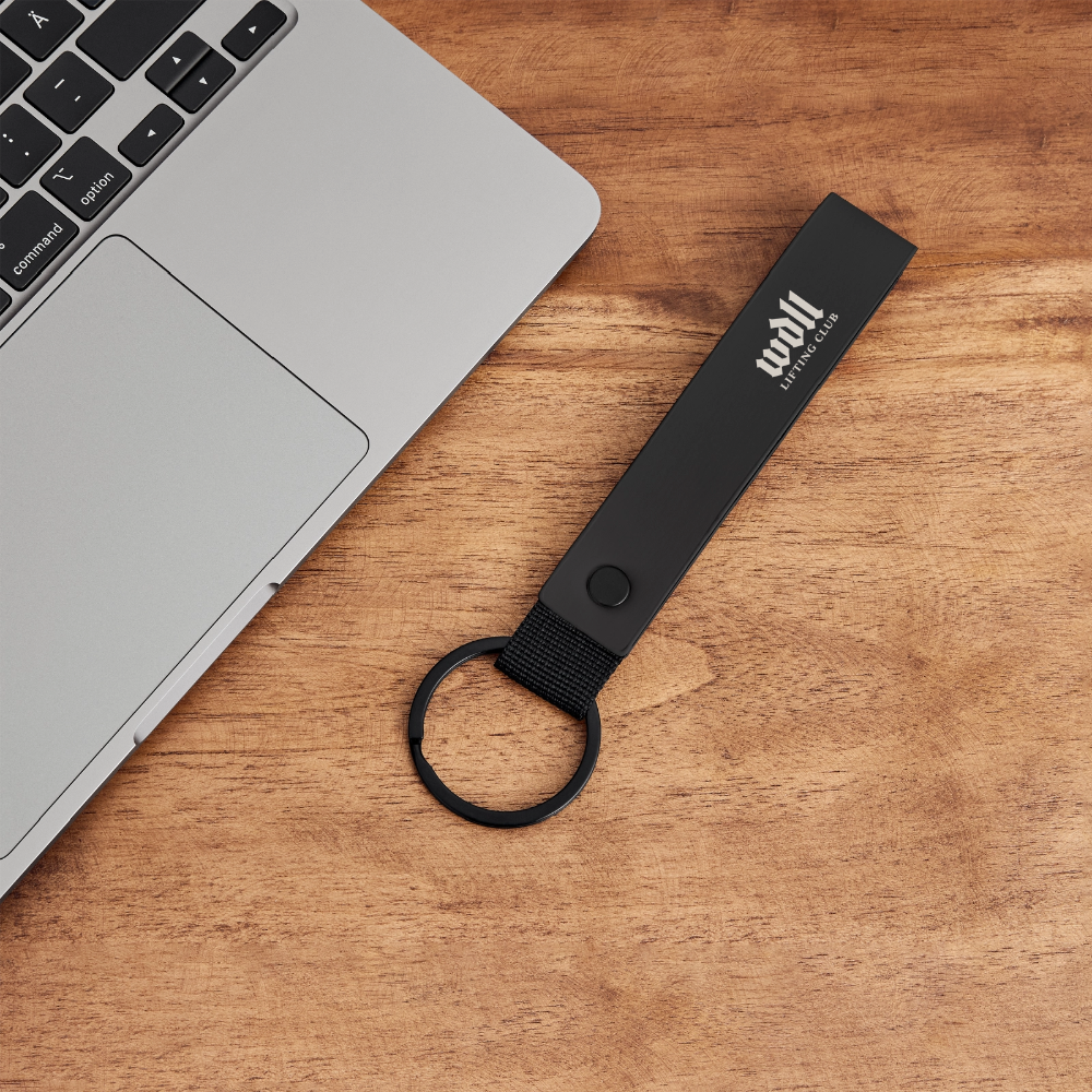 Porte-clés WDLL Lifting Club noir posé sur un bureau – WOD.LOL